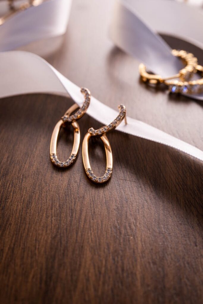 Close-up of gold hoop earrings with diamonds on wood and ribbon background.